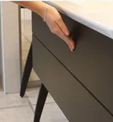 Elegant and modern bathroom inspiration with dark marble walls, round illuminated mirrors with black frames, wall-mounted vanity unit with double sinks, and a spacious shower area