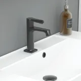 Stylish bathroom inspiration with beige vanity unit with inner drawer, upper cabinet, open shelf, oval mirror with lighting, matching pendants, shelf under the mirror, and wall-mounted toilet. Walls with light, elongated tiles