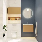Small, stylish bathroom with dark blue walls, soft yellow bathroom furniture with grooves, and an elegant round mirror with lamp