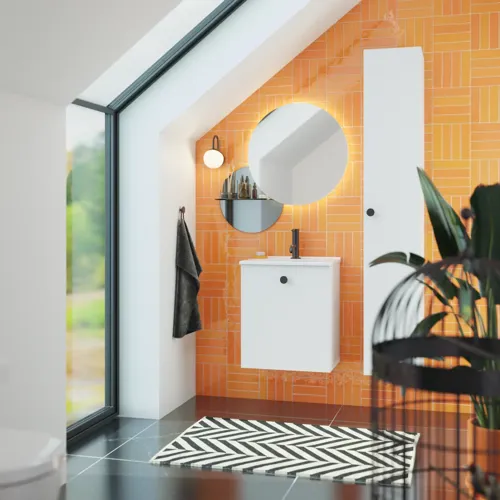 Bathroom with sloping ceiling inspiration with small white vanity unit and tall cabinet with round black handles, as well as beautiful round mirror, orange tiles give a fresh and modern look.