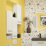 Small bathroom inspiration with a white vanity with black handle and black elegant sink, beautiful round mirror with black edge, offset wall cabinets, and terrazzo wall and floor, as well as yellow walls, provide a bold and modern look.