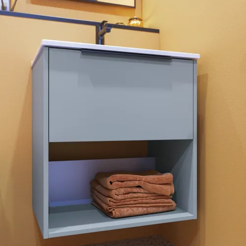 Small bathroom inspiration with slanted and warm yellow walls, an elegant light blue vanity unit with an open space that creates a unique atmosphere, and a thin, sleek sink that adds practicality and elegance to your bathroom.
